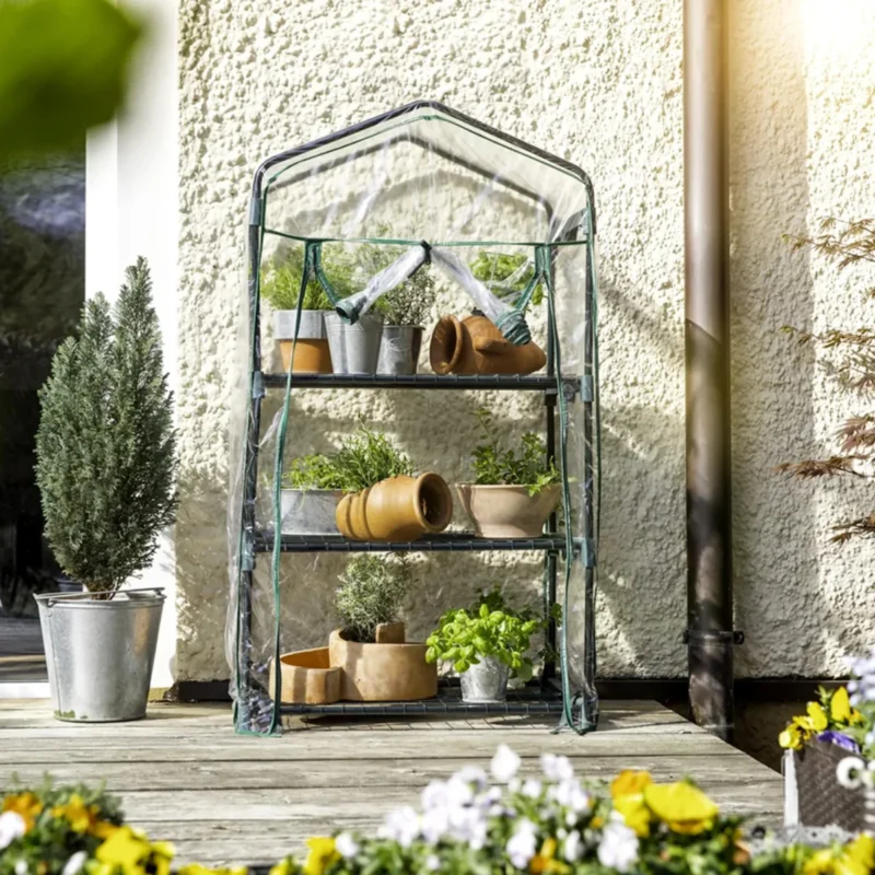 Оранжерия Windhager с три рафта, поставена на тераса с растения и саксии, подходяща за домашно отглеждане на билки и цветя