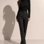 Дамска черна елегантна блуза с поло яка и дълги ръкави, носена от модел в цял ръст, комбинирана с панталон