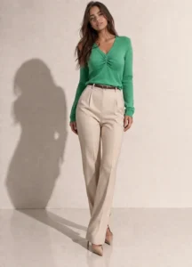 Дамска зелена блуза с V-образно деколте и дълги ръкави, носена от модел в цял ръст, комбинирана с бежов панталон