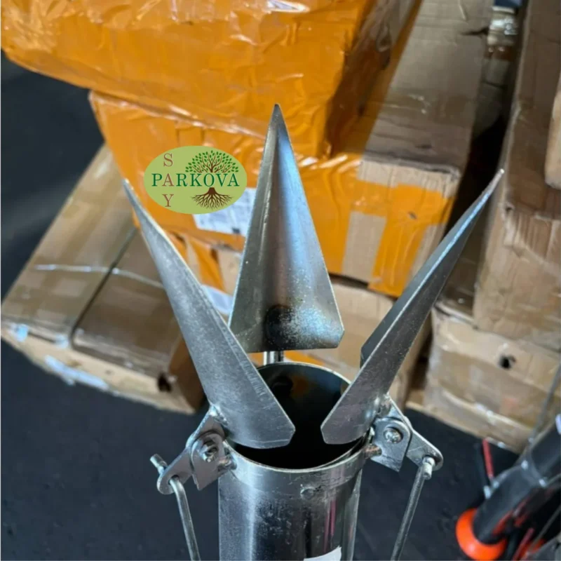 Показан е отвореният връх на машината за садене на разсад, който се забива в почвата отблизо.